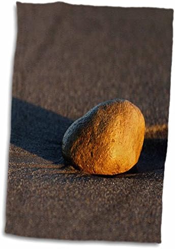אבן תדרו בחוף החוף בחול לאורך זמן השקיעה. - מגבות